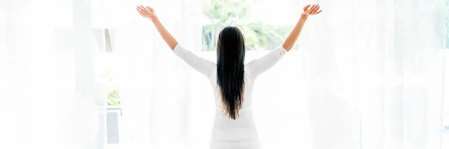 woman standing in front of window enjoying the sunshine